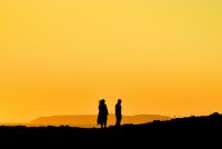 Silhouette opname van twee mensen tegen de oranje avondlucht.
